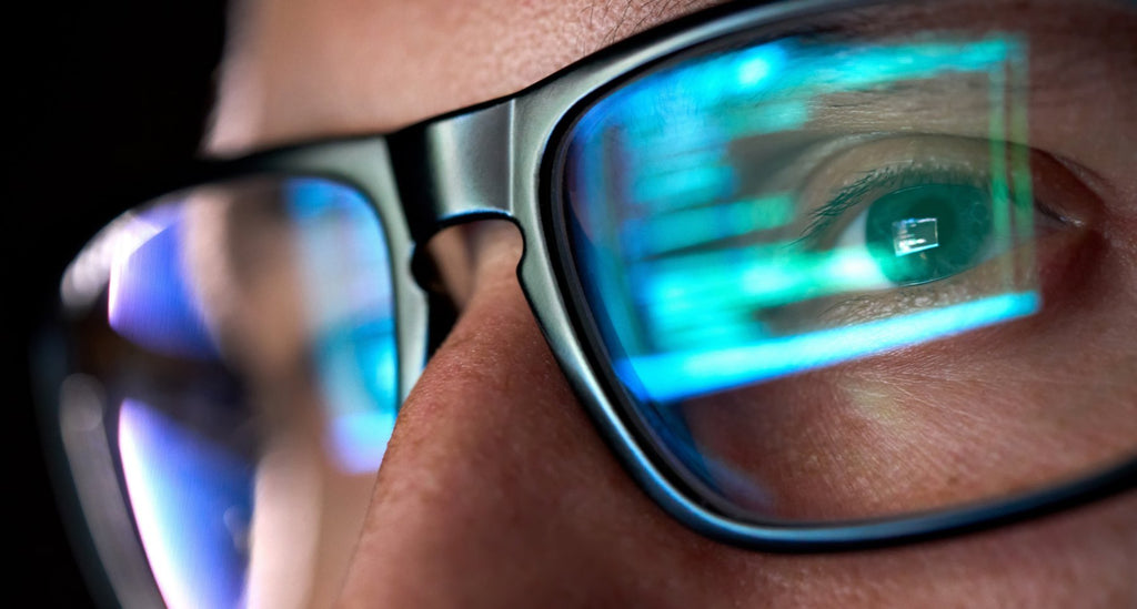 Close up of the face of an ethical hacker with reflection of computer screen on his lenses