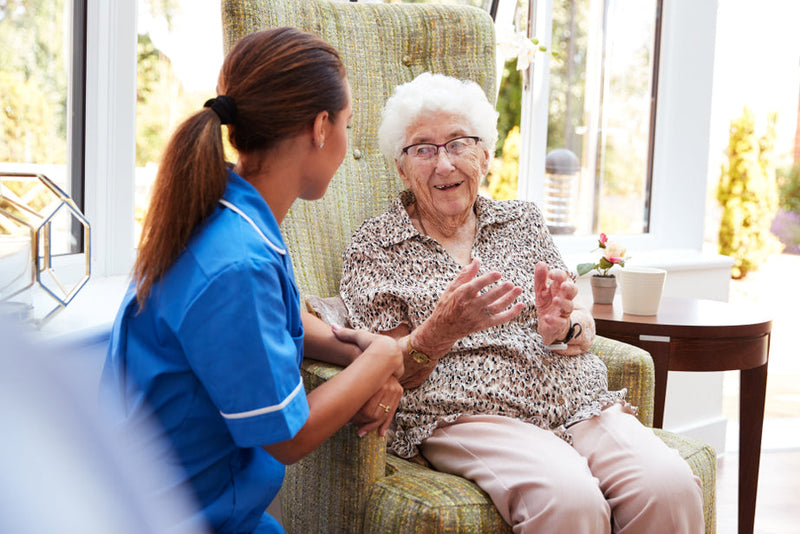 Nurse interacting with an elderly woman in a home setting