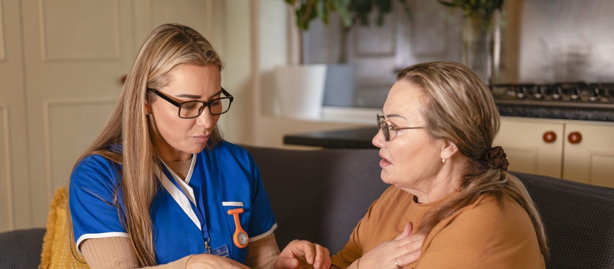 Healthcare worker provides support and guidance to a senior woman in a home setting during the daytime