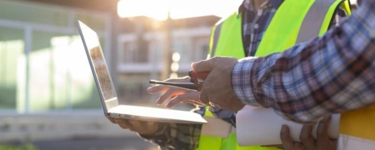 2 construction workers looking at a laptop screen