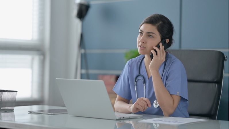 Care provider at a desk using a laptop whilst on the phone