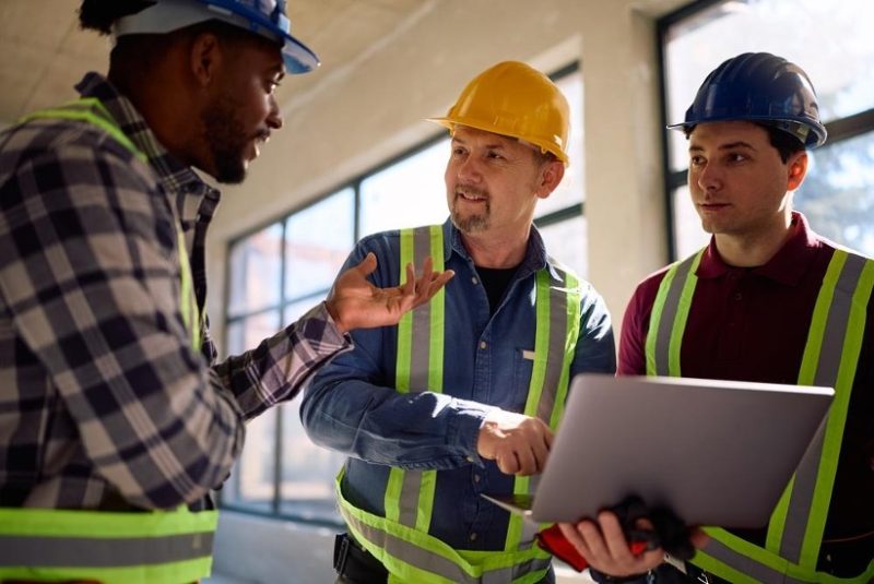 Construction workers holding laptop and discussing the job